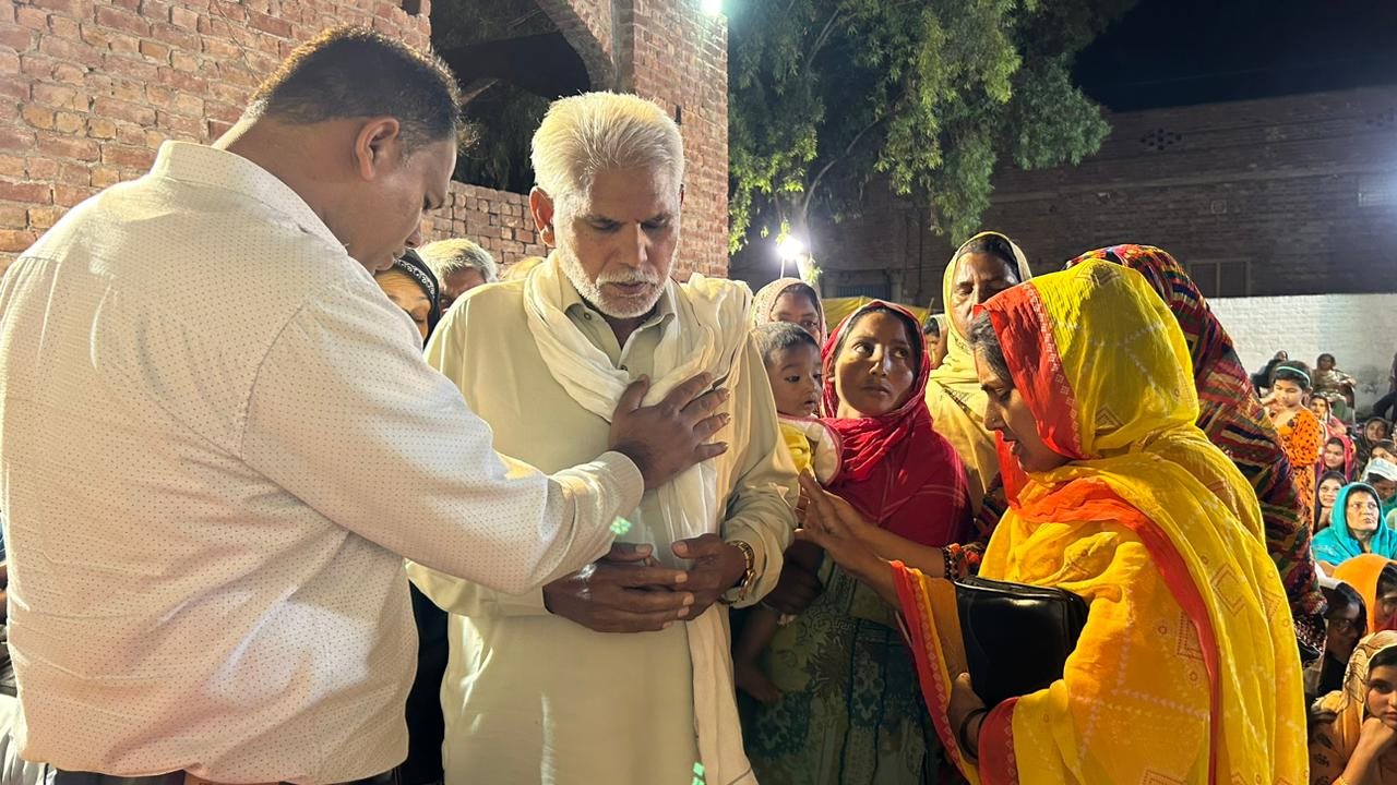 A ministry leader praying with community members